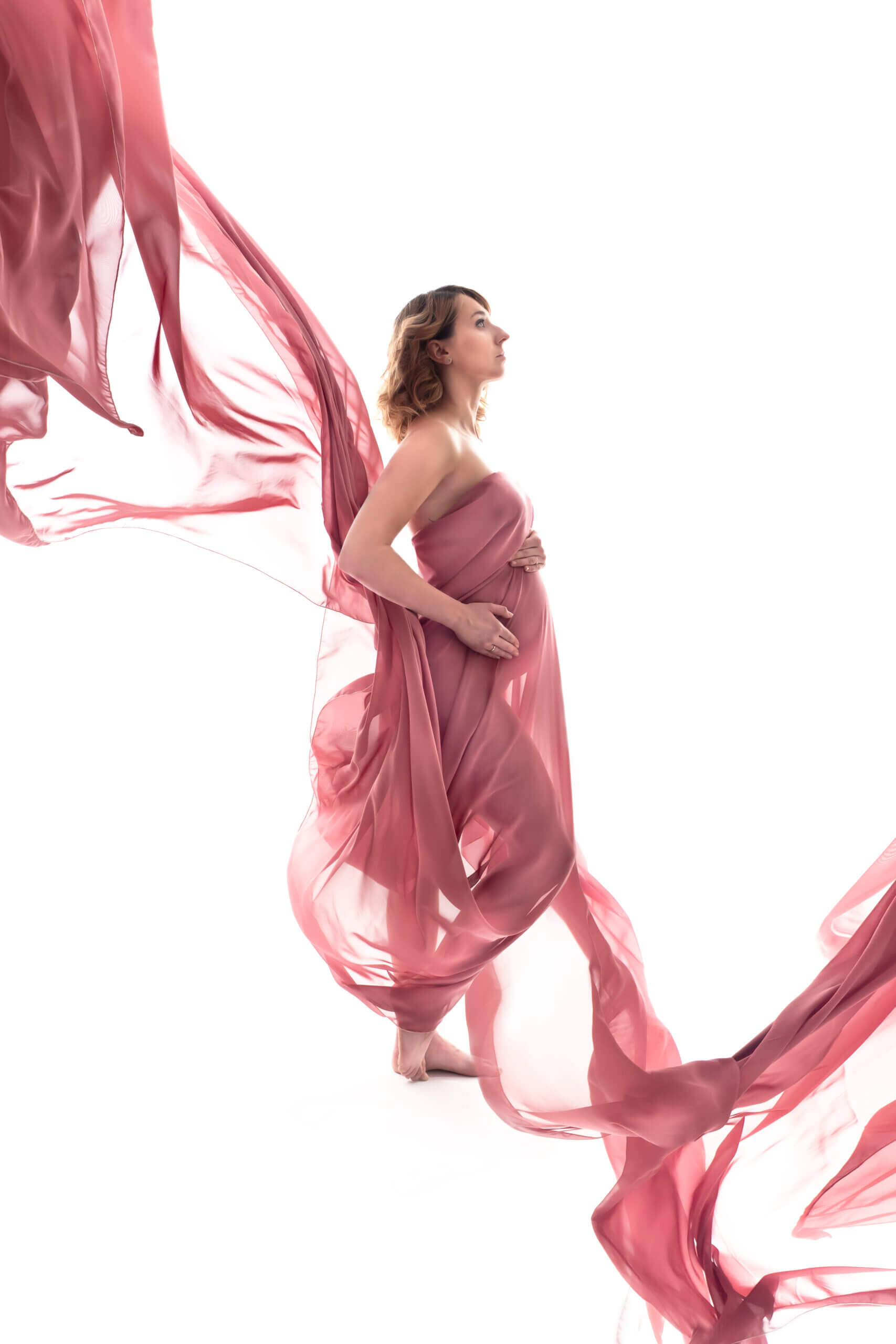 fotografia ciążowa, dynamiczny rzucany różowy szyfon na białym