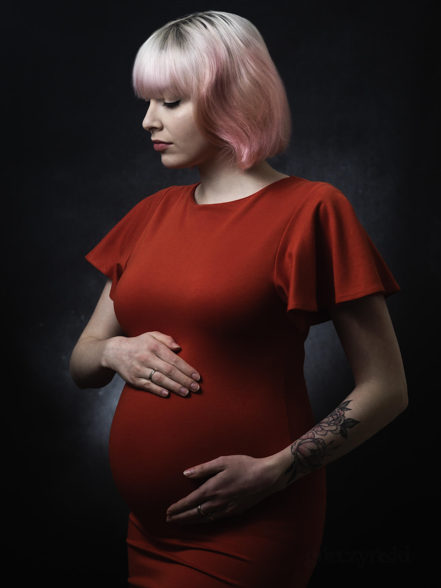 fotografia ciążowa, kobieta w czerwonej sukience na ciemnym tle